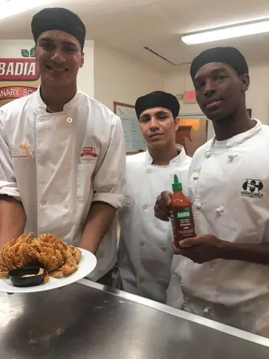 Culinary students proudly presenting fried chicken at Here's Help Inc, an intensive outpatient program in Miami.